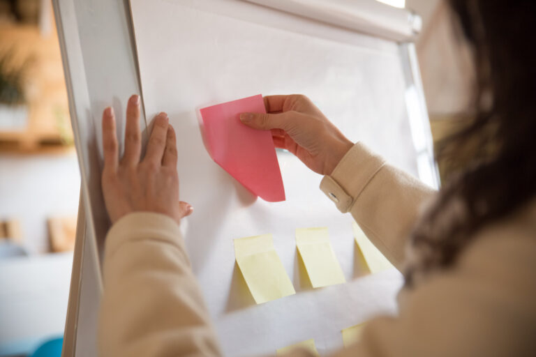 Female manager sticking blank paper notes on flipchart